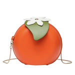 Orange fruit shaped crossbody bag with green leaves and gold chain strap.