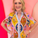 Colorful floral mosaic blouse with blue trim and split neckline.