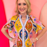 Colorful floral mosaic blouse with blue trim and split neckline.