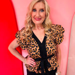Leopard peplum top with flutter sleeves and black trim.