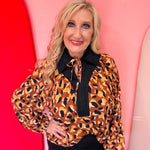 Leopard print blouse with black trim and tie neckline.