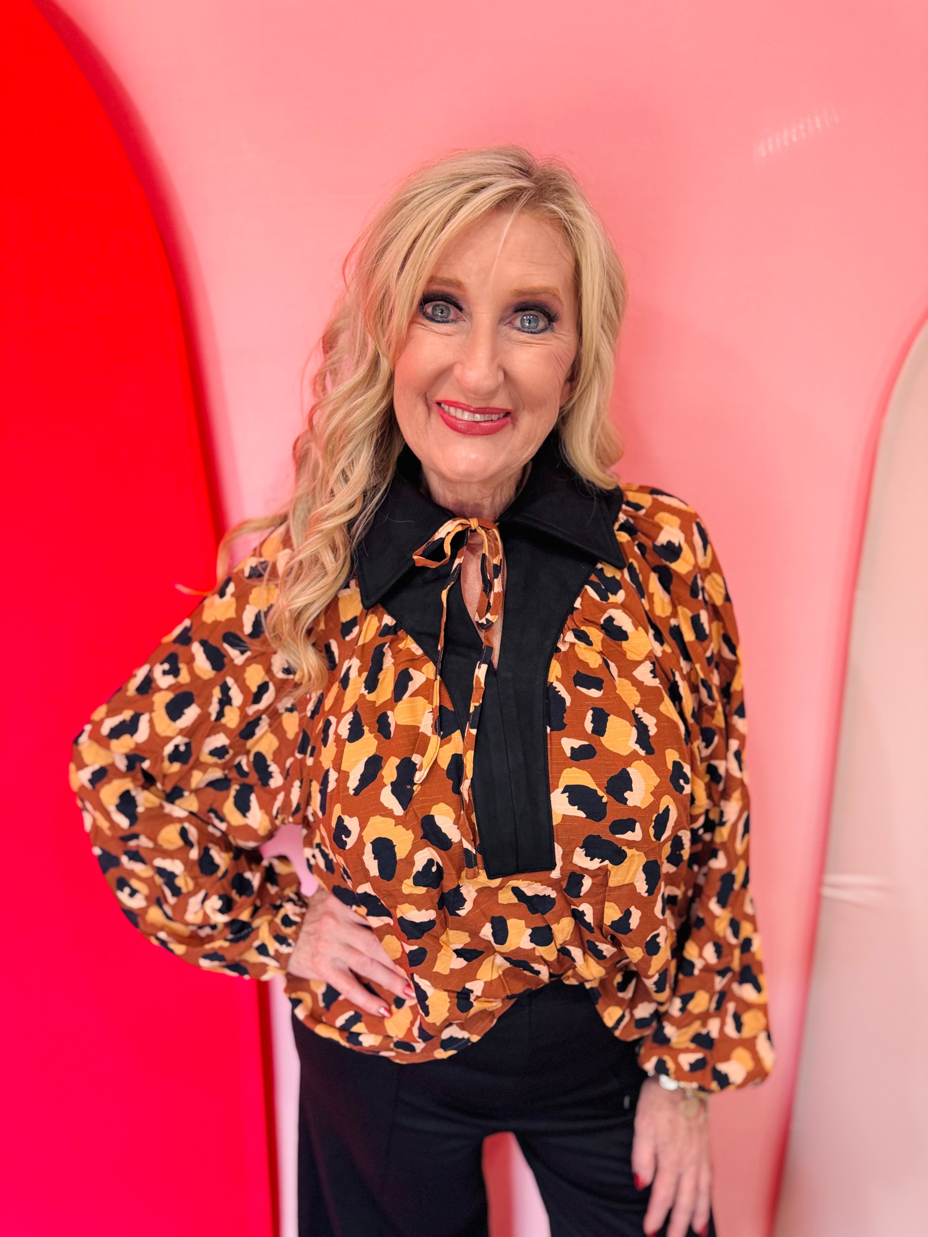 Leopard print blouse with black trim and tie neckline.
