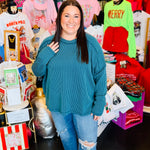 Plus-size teal ribbed boat neck long sleeve top with raw edge detailing.