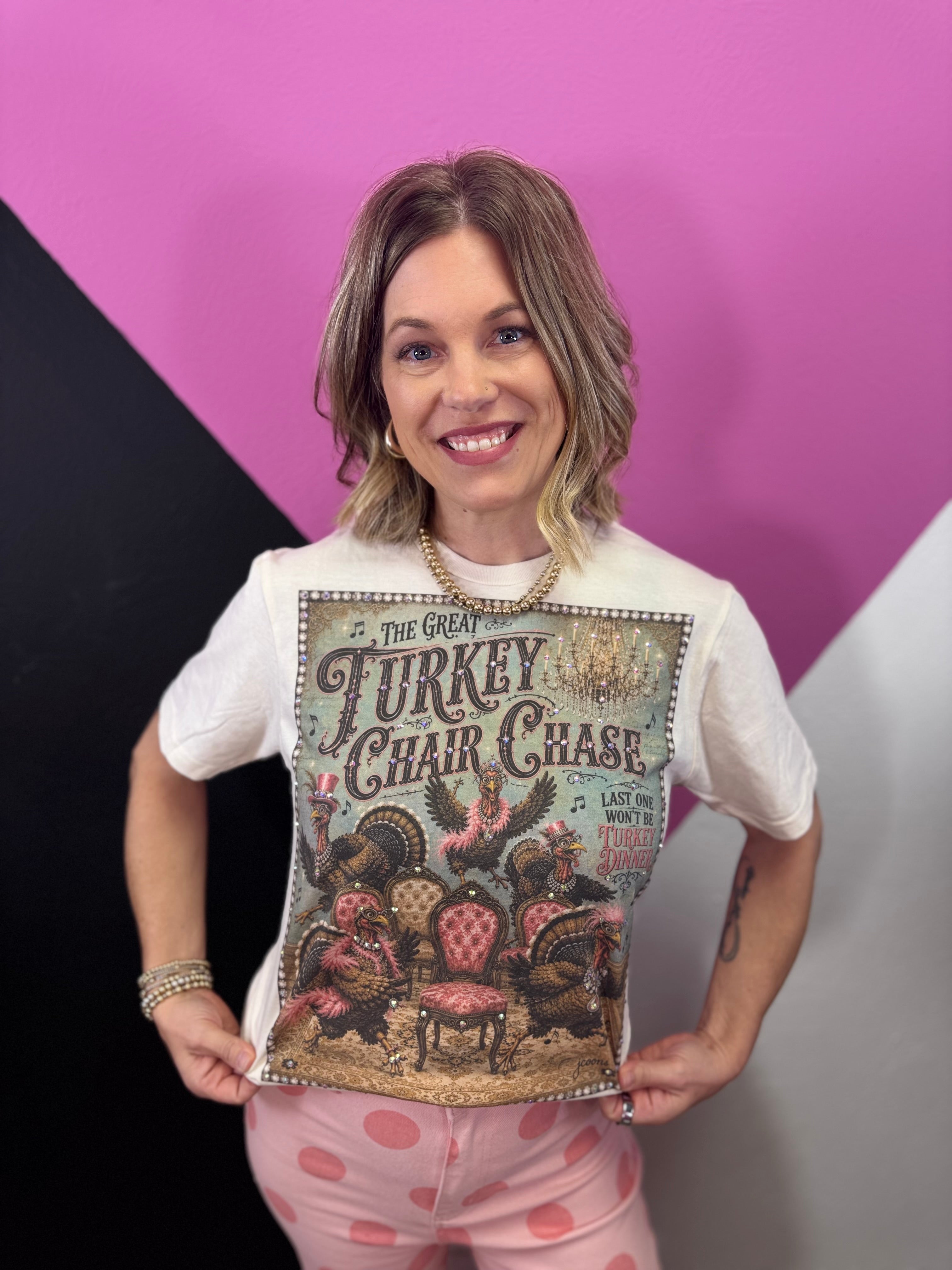 Cream Thanksgiving tee with dressed-up turkeys, colorful chairs, vintage artwork, and sparkling details.