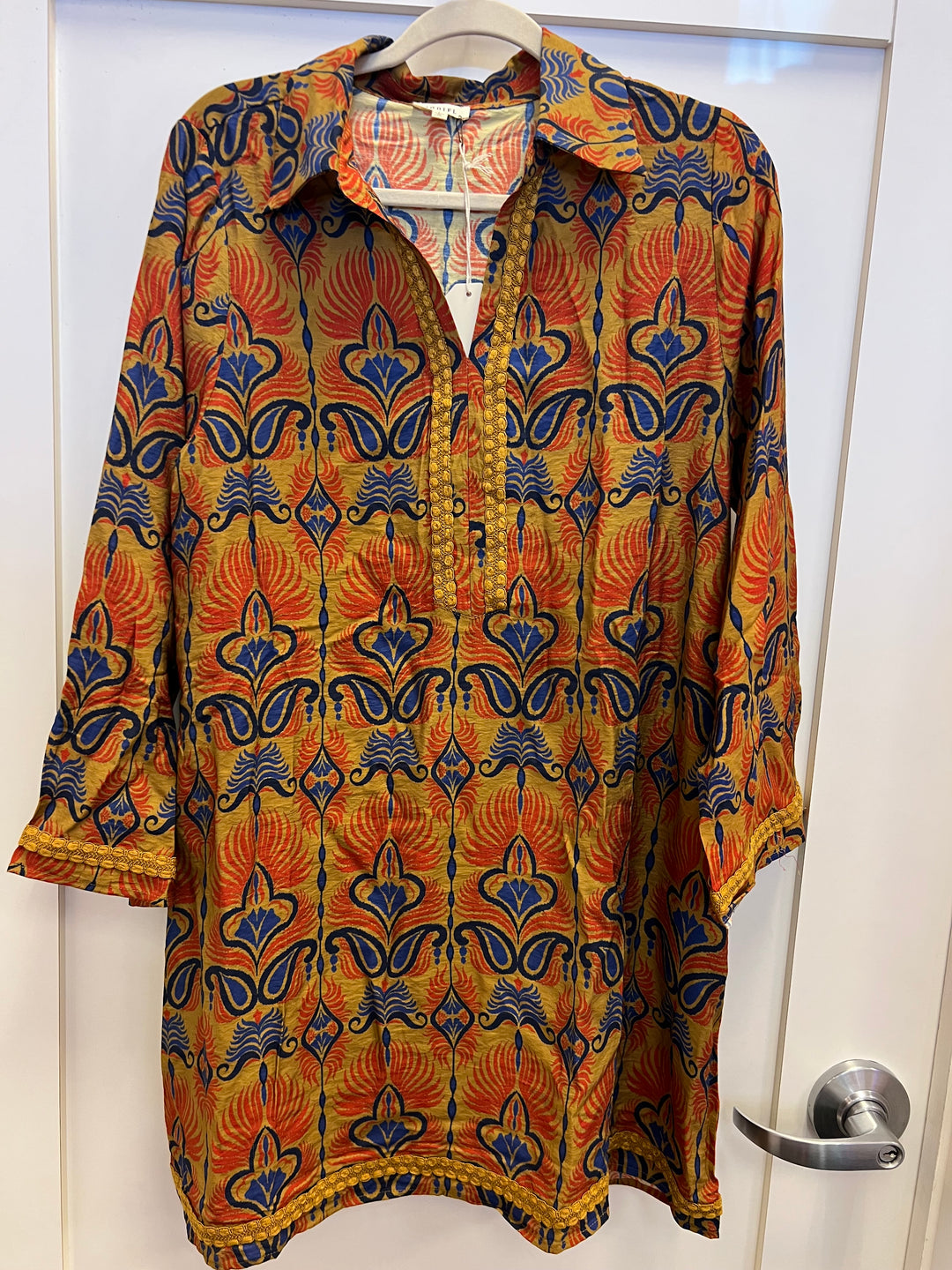 Toffee Boho Print Dress with orange, gold, and navy pattern, collared neckline, cotton braided trim, and pockets.
