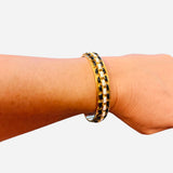 Gold-tone cuff bracelet with black and ivory enamel woven design.