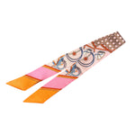 Vibrant travel silk scarf tie with oranges, pinks, golds, geometric patterns, and polka dot ends.