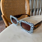 White sunglasses with black polka dots and brown side detail in rectangular frame