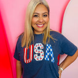 Navy USA graphic tee with cherries, stripes, and blue checkered lettering