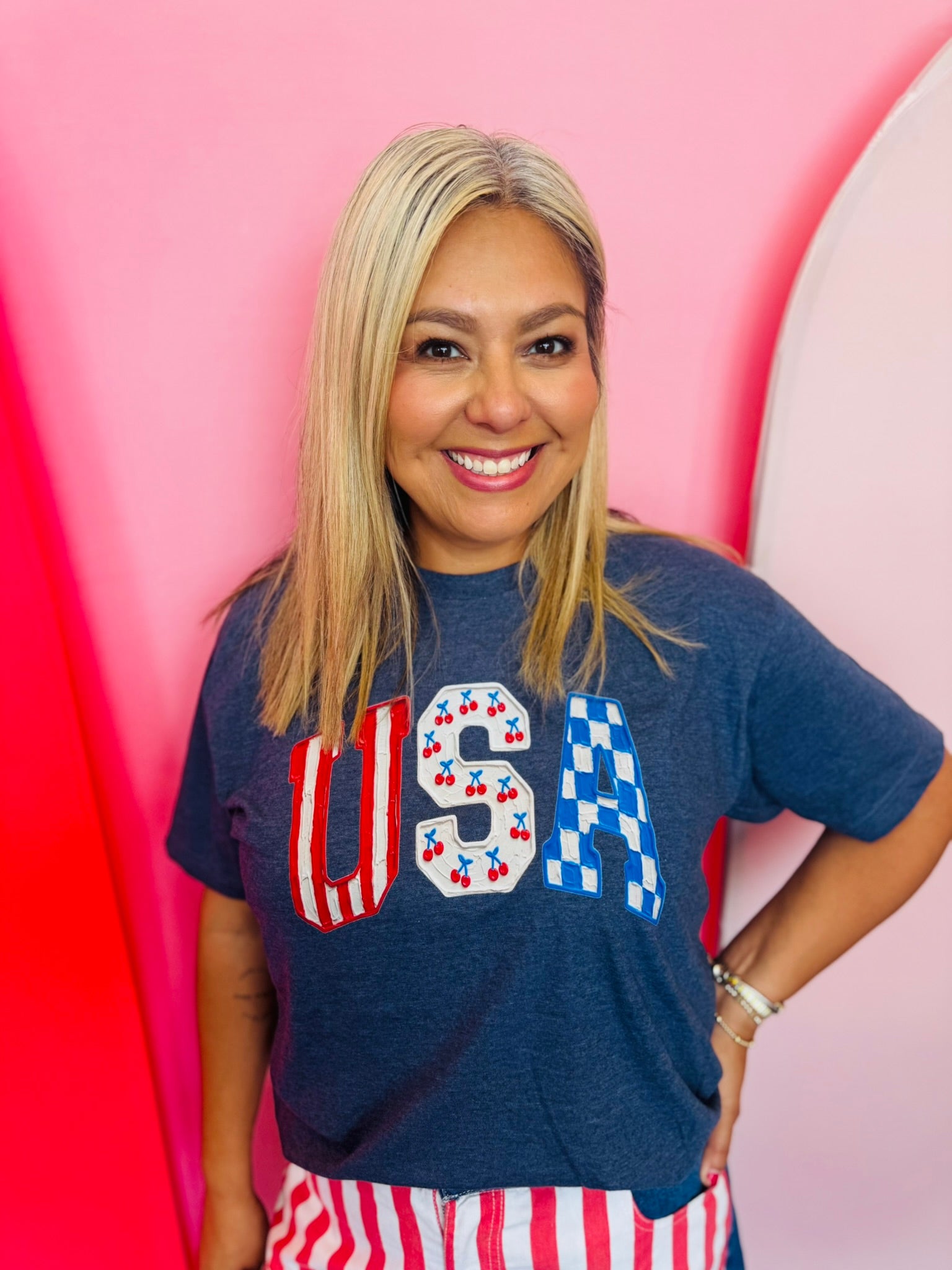 Navy USA graphic tee with cherries, stripes, and blue checkered lettering