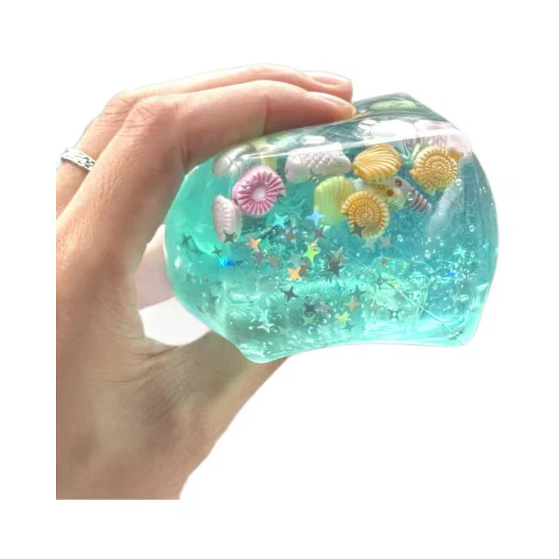 Blue cube squishy with glitter, seashells, and star accents inside.