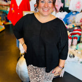 Black waffle knit V-neck top with raw front seam, 3/4 sleeves, and relaxed fit.