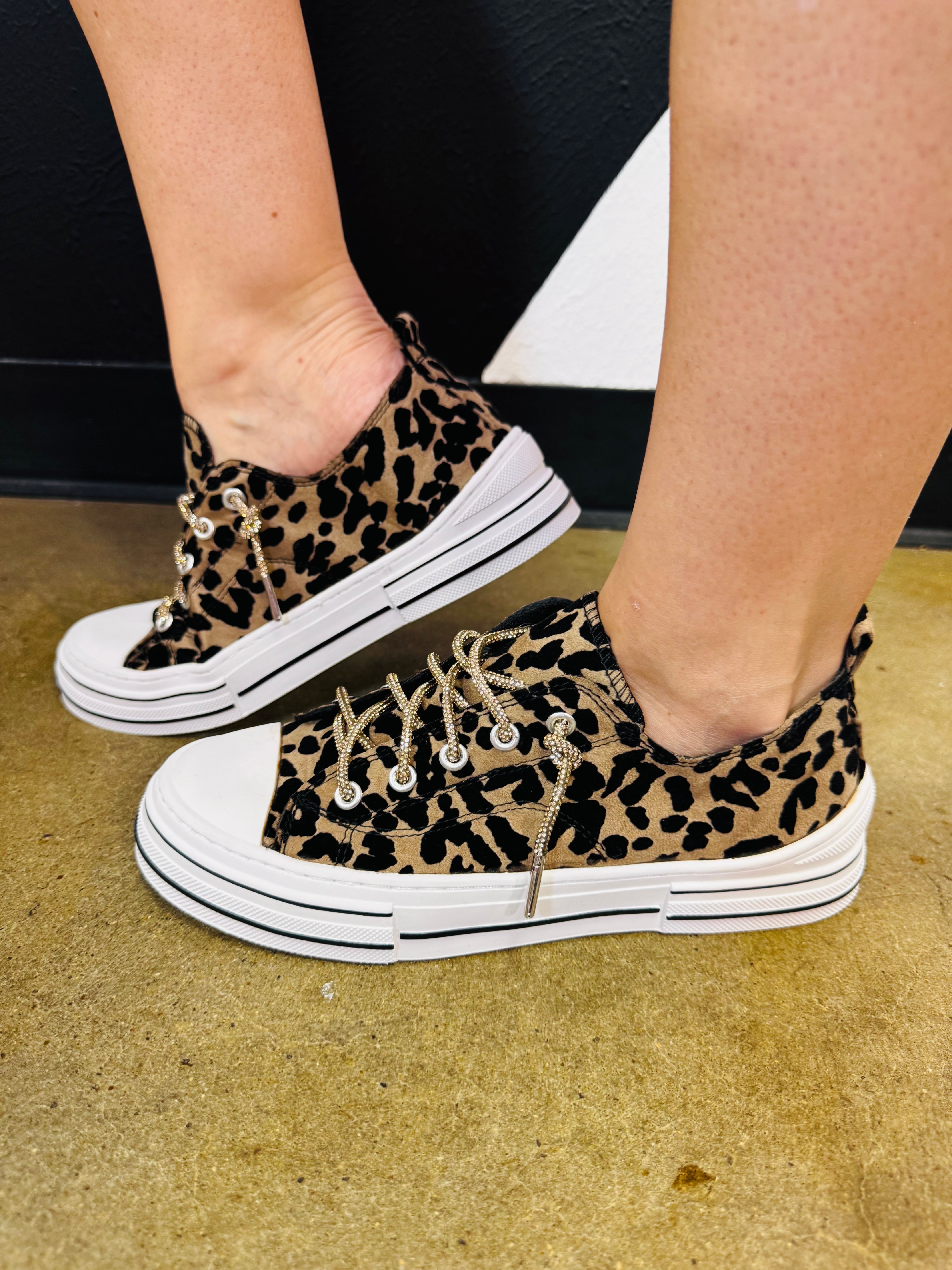 Leopard print sneakers with sparkling rhinestone laces, white rubber toe, and chunky platform sole.