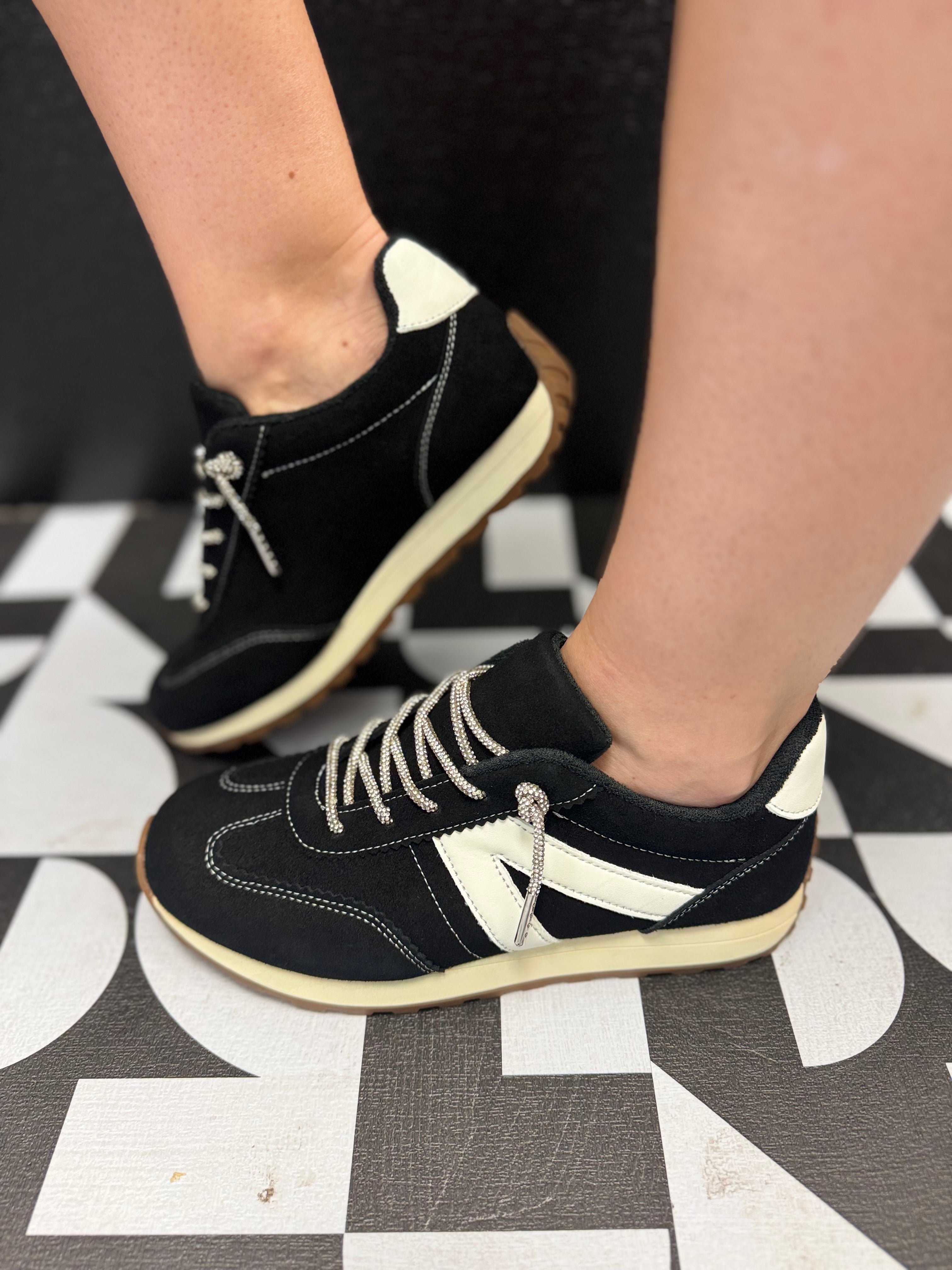 Black Very G sneakers with white accents, rhinestone laces, detailed stitching, and neutral sole.