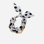 White polka dot knot bracelet with black dots and gold chain accents.