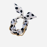 White polka dot knot bracelet with black dots and gold chain accents.