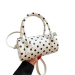 White polka dot crossbody bag with adjustable strap and top handles.