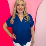 Navy woven blouse with V-neckline and cuffed short sleeves.