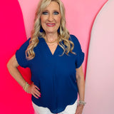 Navy woven blouse with V-neckline and cuffed short sleeves.