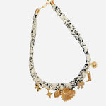 Black-and-white fabric scarf necklace with gold heart, starburst, boot, bow, and lucky charms.