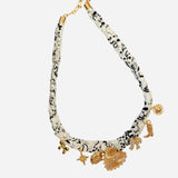 Black-and-white fabric scarf necklace with gold heart, starburst, boot, bow, and lucky charms.