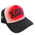 Black trucker hat with white front panel and bold red XOXO Valentine design