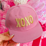 Pink XOXO embroidered baseball cap with gold lettering and adjustable snapback closure