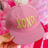 Pink XOXO embroidered baseball cap with gold lettering and adjustable snapback closure