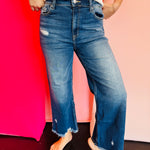 Blue denim distressed jeans that have a straight-leg fit and a raw, frayed hemline that hits above the ankle.