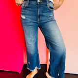 Blue denim distressed jeans that have a straight-leg fit and a raw, frayed hemline that hits above the ankle.