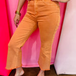 Orange cropped bootcut jeans with frayed hem and high-rise fit.