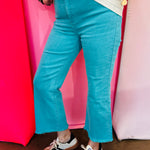 Turquoise cropped bootcut jeans with frayed hem and high-rise fit.