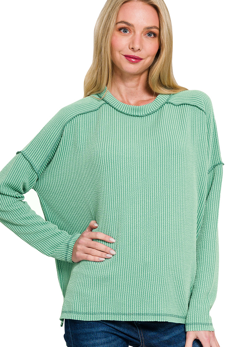 A light jade ribbed boat neck top. The top has long sleeves, a relaxed fit, and raw edge details on the seams