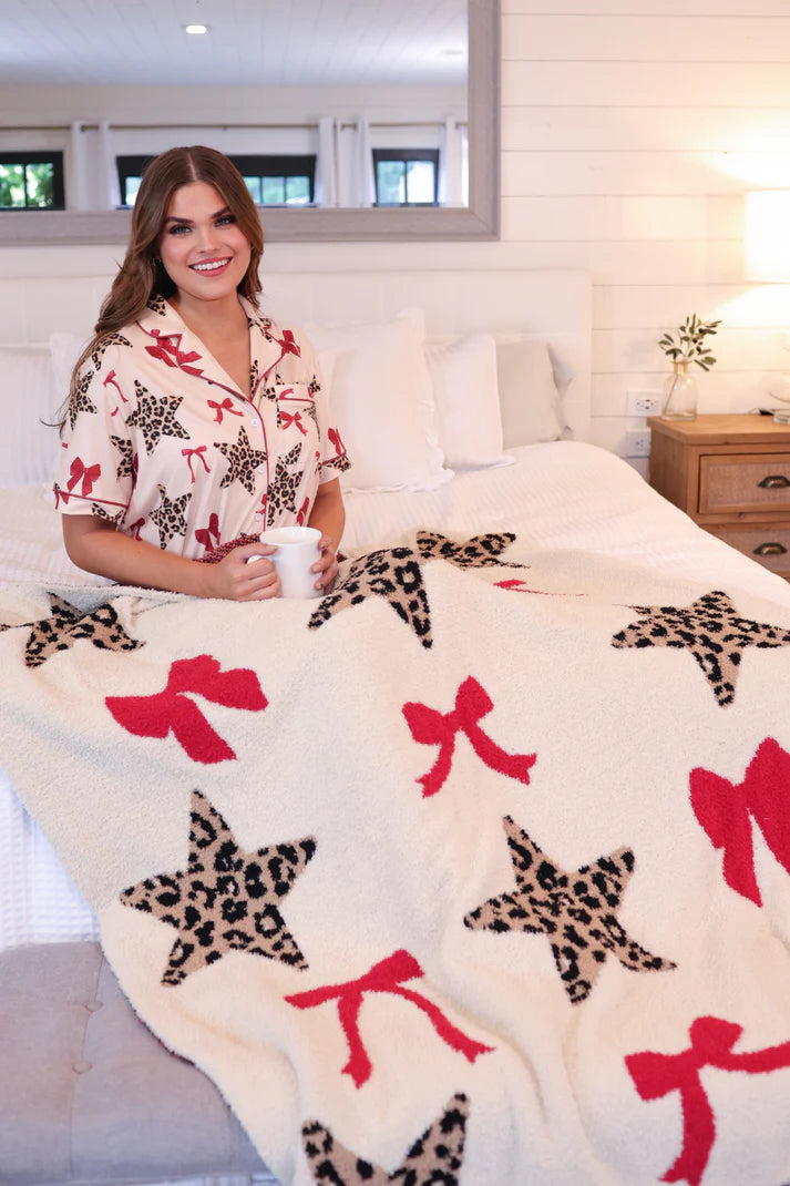 Soft throw blanket featuring a playful leopard star and bow print, sized 50 x 57 inches, displayed folded on a neutral surface.
