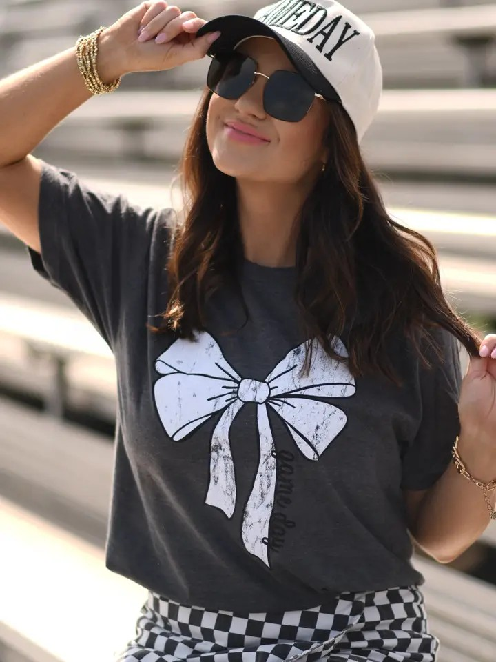 Heather charcoal Tultex tee with a white bow and bold black “game day” lettering at the bottom, displayed flat.