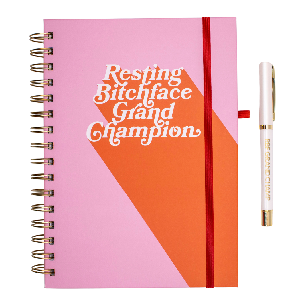 Pink and coral RBF Grand Champion journal with white lettering that says “Resting Bitchface Grand Champion,” matching pen, A5 hardcover, and 140 pages.