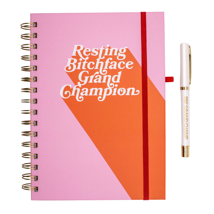 Pink and coral RBF Grand Champion journal with white lettering that says “Resting Bitchface Grand Champion,” matching pen, A5 hardcover, and 140 pages.