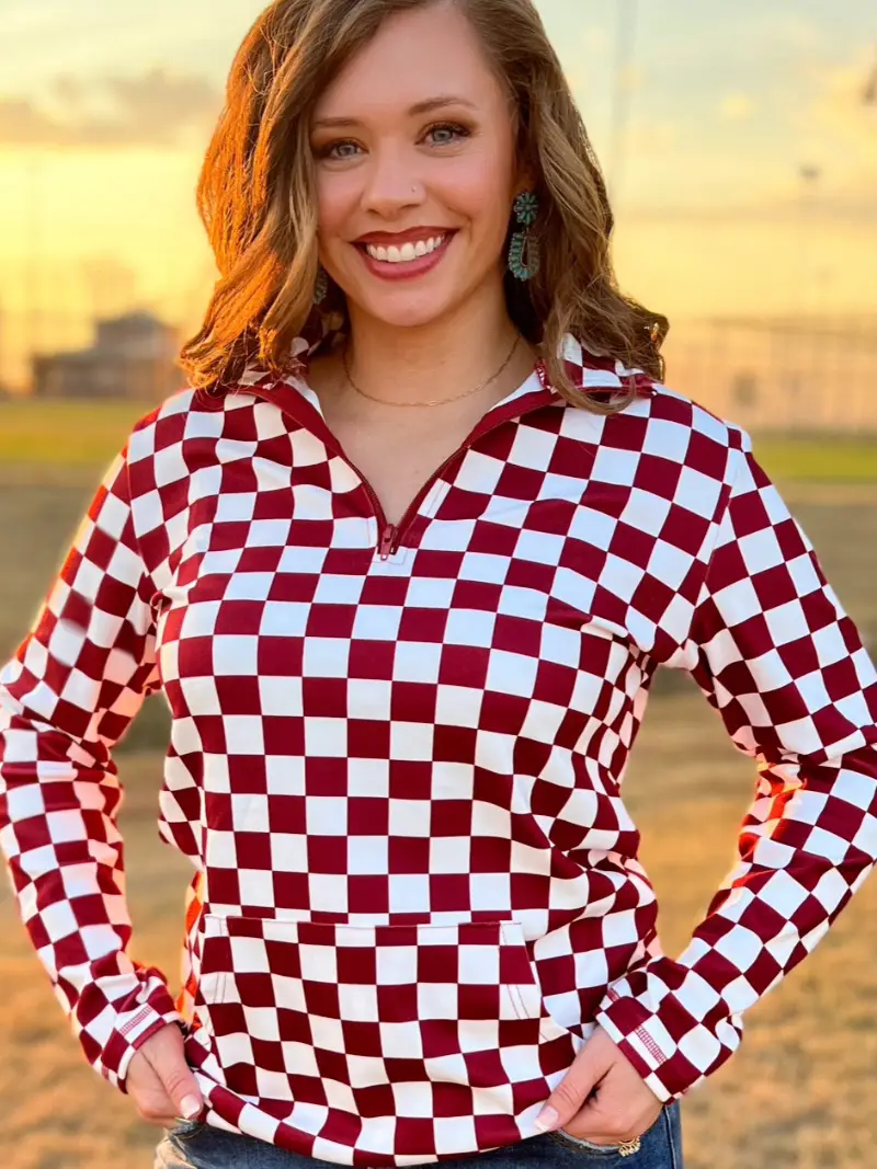 Maroon and white checkered pullover with a collared neckline, quarter-zip front, and kangaroo pocket, laid flat to showcase the bold pattern and design.