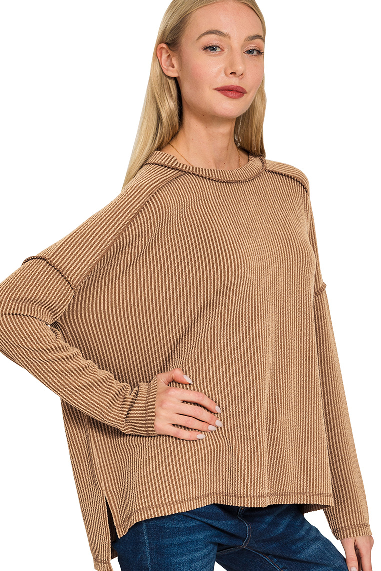 A camel ribbed boat neck top. The top has long sleeves, a relaxed fit, and raw edge details on the seams.