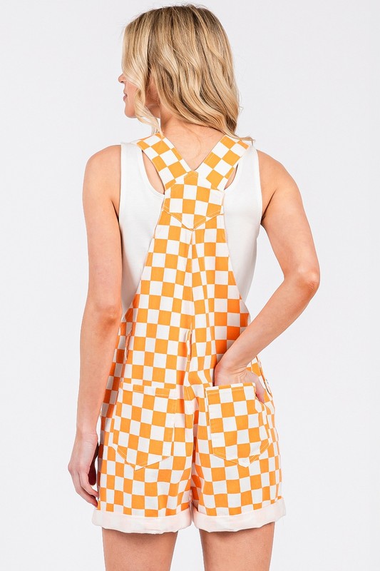 Orange checkered knit romper overalls with cuffed shorts, adjustable straps, and multiple pockets, laid flat to show texture and design.