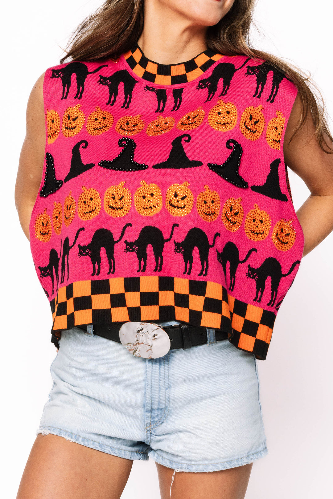 Queen of Sparkles Halloween-themed sleeveless top with pumpkins, cats, and witch hats on a pink Sweater with checkered black and orange on the top and bottom