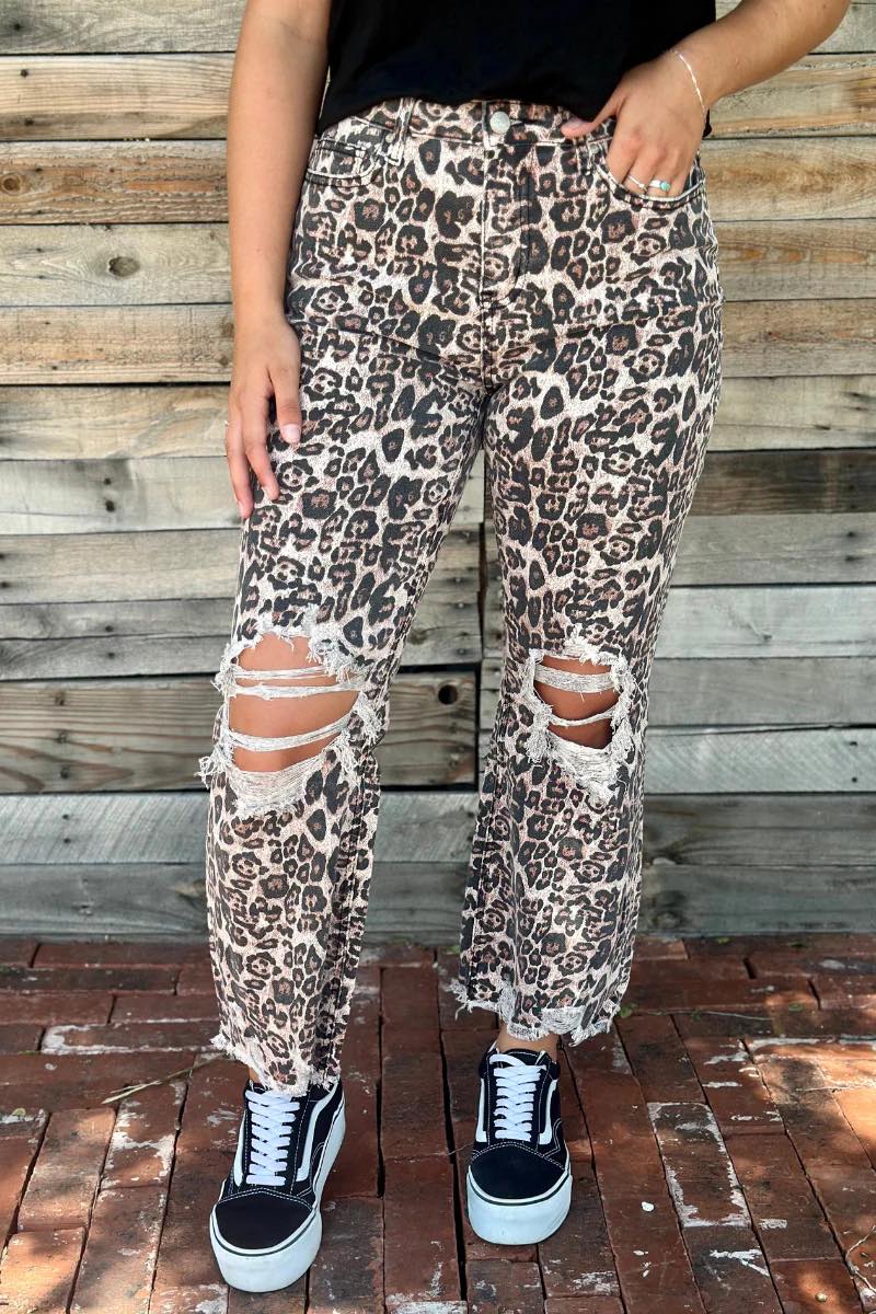 Distressed leopard print jeans with knee rips, frayed hems, and high-rise straight-leg fit.