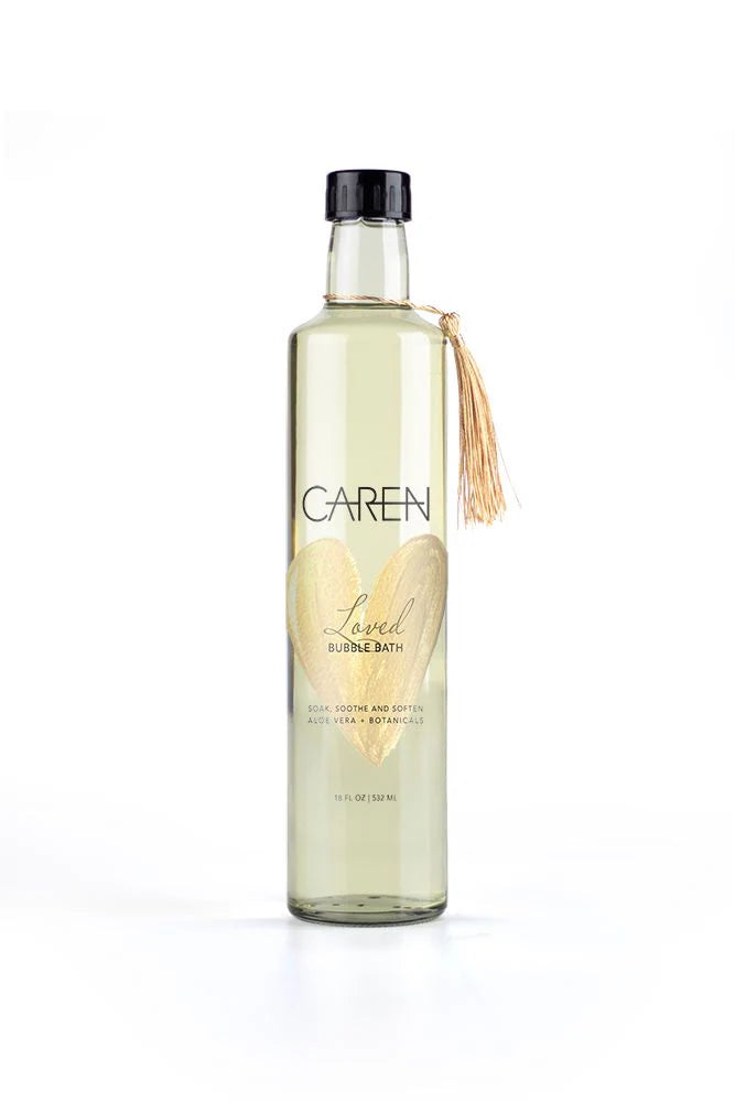 A sophisticated, clear glass bottle of "Loved" bubble bath.