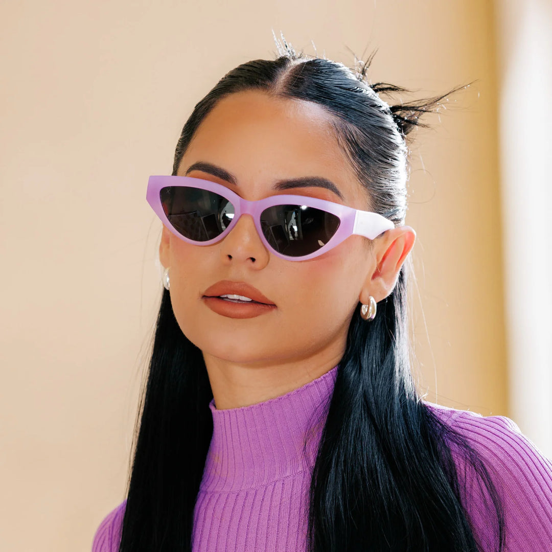 A woman wearing lavender-colored cat-eye polarized sunglasses with a purple top.