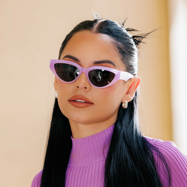A woman wearing lavender-colored cat-eye polarized sunglasses with a purple top.