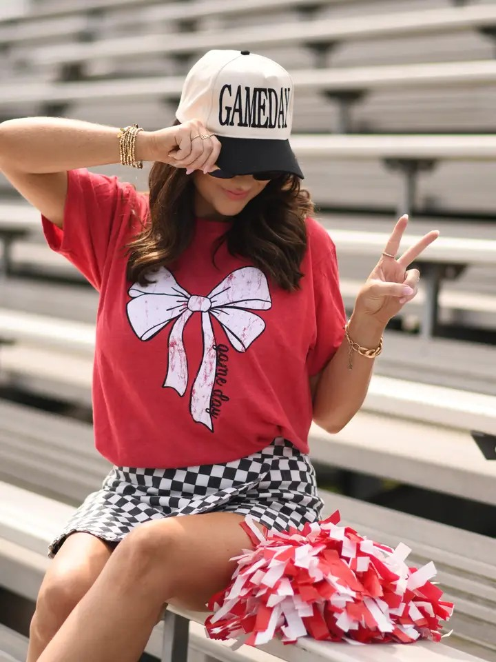 Red Tultex tee with a large white bow and bold black “Game Day” text on front, laid flat for display.