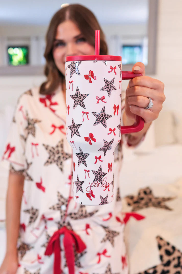 Simply Untamed 40 oz tumbler with a leopard star and bow print, featuring a built-in handle, reusable straw, screw-on lid, and car cup holder-friendly base. Stylish and functional drinkware for on-the-go hydration.