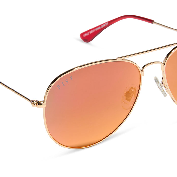 Close-up shot highlighting the red mirrored polarized lenses and gold stainless steel frame details.