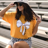 Gold Tultex tee with a white bow and bold black “game day” text at the bottom, displayed flat.