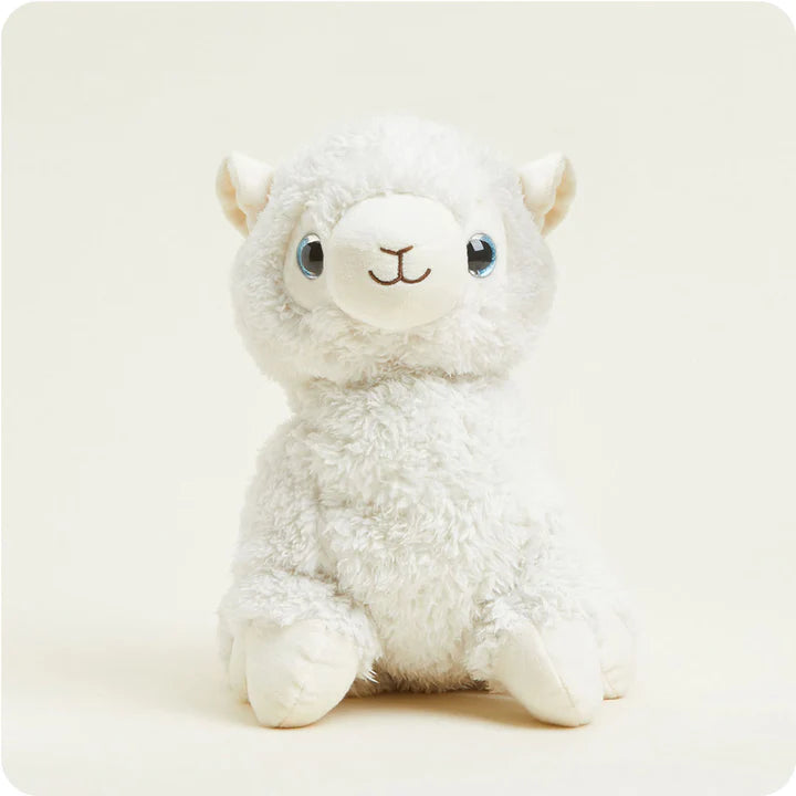 A soft, white plush llama toy with a colorful saddle on its back, designed to be microwavable.
